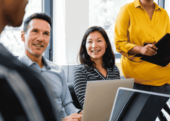 Woiman sitting with colleagues in a meeting smiling after support with ADA Accommodations for mental health