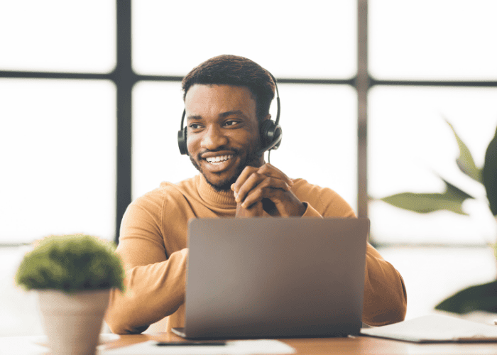 Man sitting at desk with laptop and headphones smiling after seeking support with mental health and job protection