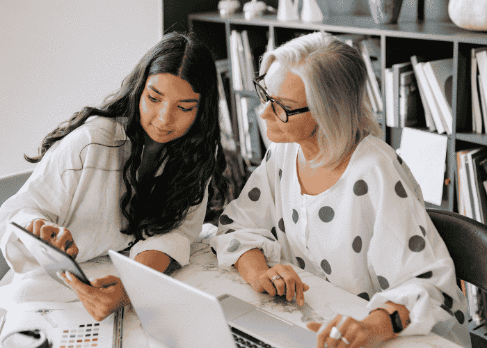 A woman sat at a desk with a colleague discussing confidentiality in the workplace