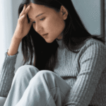 Woman sitting at home on sofa needing support with a return to work plan after mental health leave