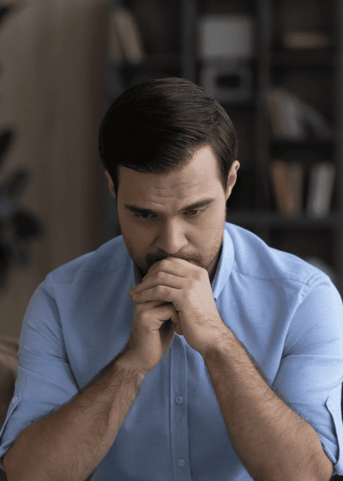 Man sitting on couch with chin resting on his hands worrying about memory processing in PTSD