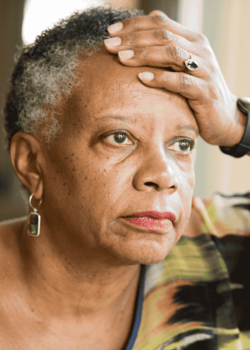 Woman sitting with hand on head looking out window wondering about lifestyle psychiatry approach to mental health