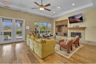 Sunlit common lounge at a Mission Connection treatment facility with cozy seating, fireplace, and garden views for client comfort.