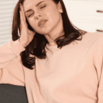Woman sitting on couch with hand on head needing support with nutrition and mood disorders