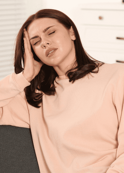Woman sitting on couch with hand on head needing support with nutrition and mood disorders