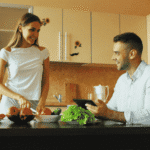 Man sitting at kitchen table with wife preparing food after support with nutrition and mood disorders