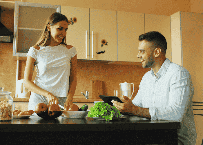 Man sitting at kitchen table with wife preparing food after support with nutrition and mood disorders