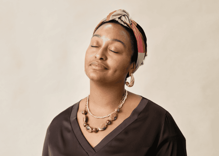 Woman standing with eyes closed smiling after support with breathwork for mental health