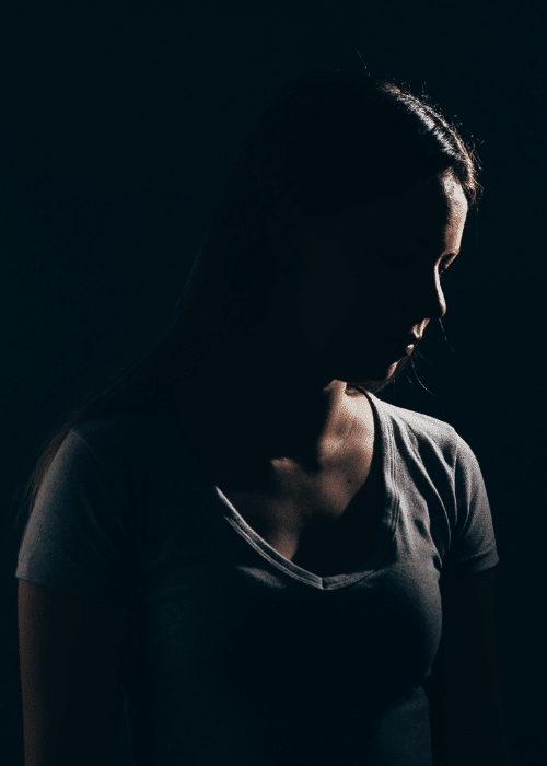 Woman stood in darkness needing support with sunlight and mood regulation