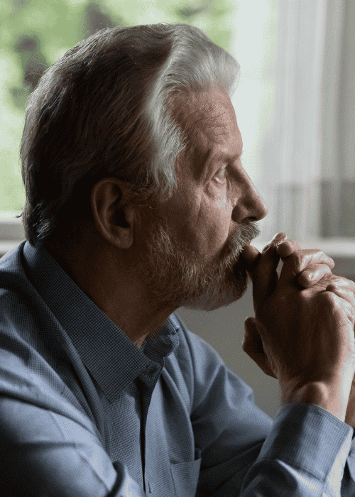 Man sitting by window resting chin on hands needing support with biohacking and mental health