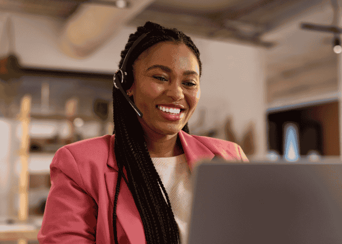 Woman sitting at desk with laptop smiling after receiving support with biohacking and mental health