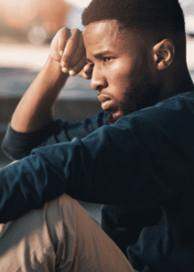 Man sitting on step outside with knees drawn to chest and head resting on hand needing support with longevity psychiatry