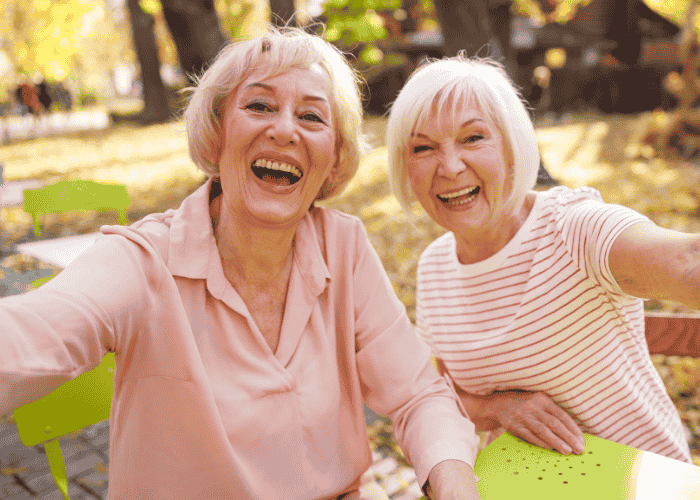 Woman sitting with friend outside in garden smiling after support with longevity psychiatry