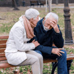 Man sitting on bench with wife with head in hand wondering how depression affects the brain.