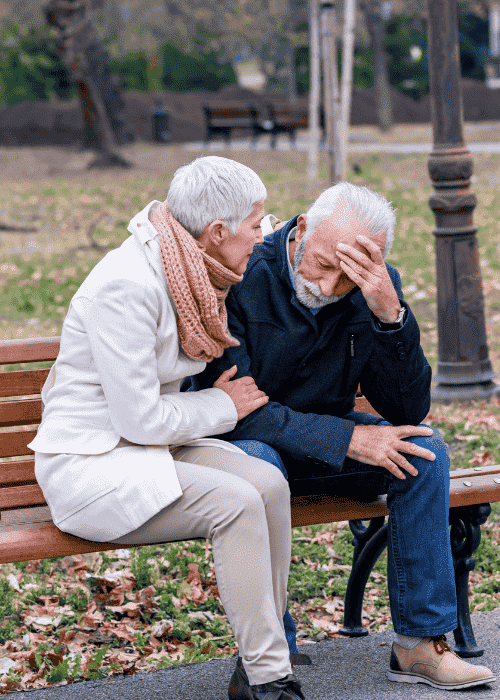 Man sitting on bench with wife with head in hand wondering how depression affects the brain.