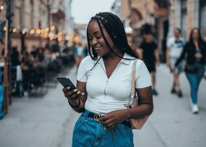 Woman walking down street looking at phone smiling after researching how depression affects the brain