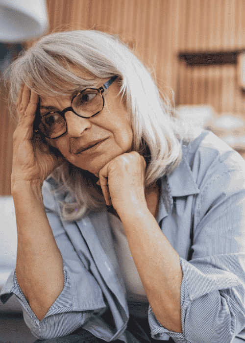 Woman sitting on couch with head in hand needing support with neuroplasticity and mental health recovery