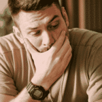 Man sitting on couch with hand over mouth needing support with how trauma affects the nervous system.