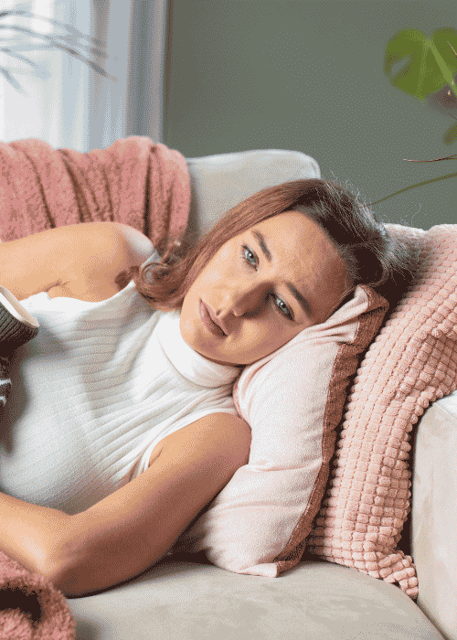 Woman laying on couch needing support with hormonal cycles and depression