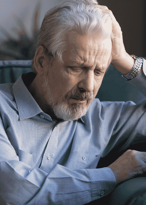 Man sitting on couch with head in hand needing support with neuropsychological assessments