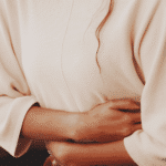 Woman sitting clutching stomach showcasing the gut-brain axis
