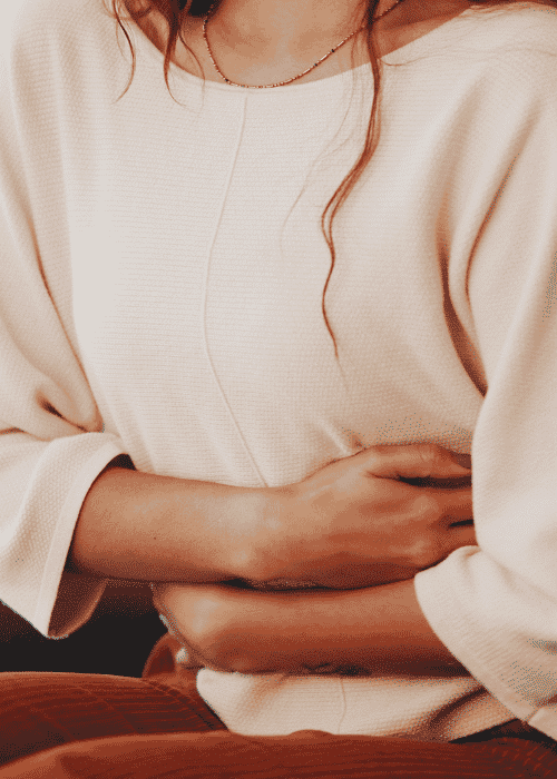 Woman sitting clutching stomach needing support with gut-brain axis