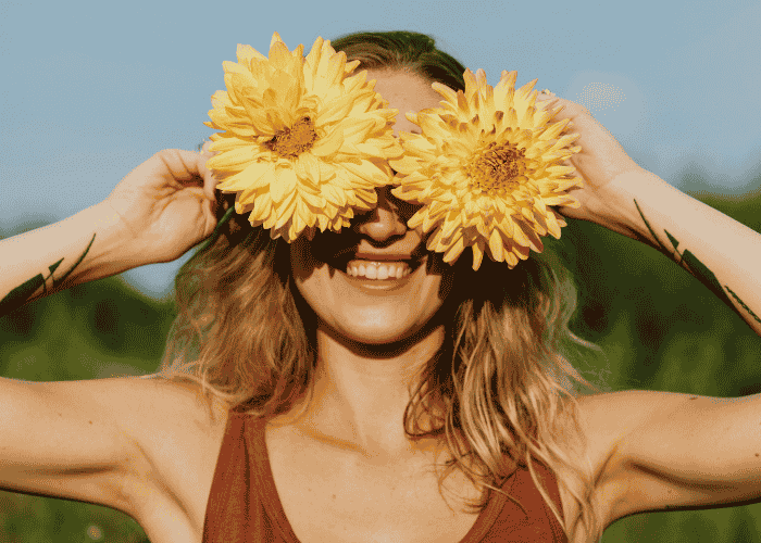 Woman with flowers over her eyes smiling after understanding neurobiology in mental health