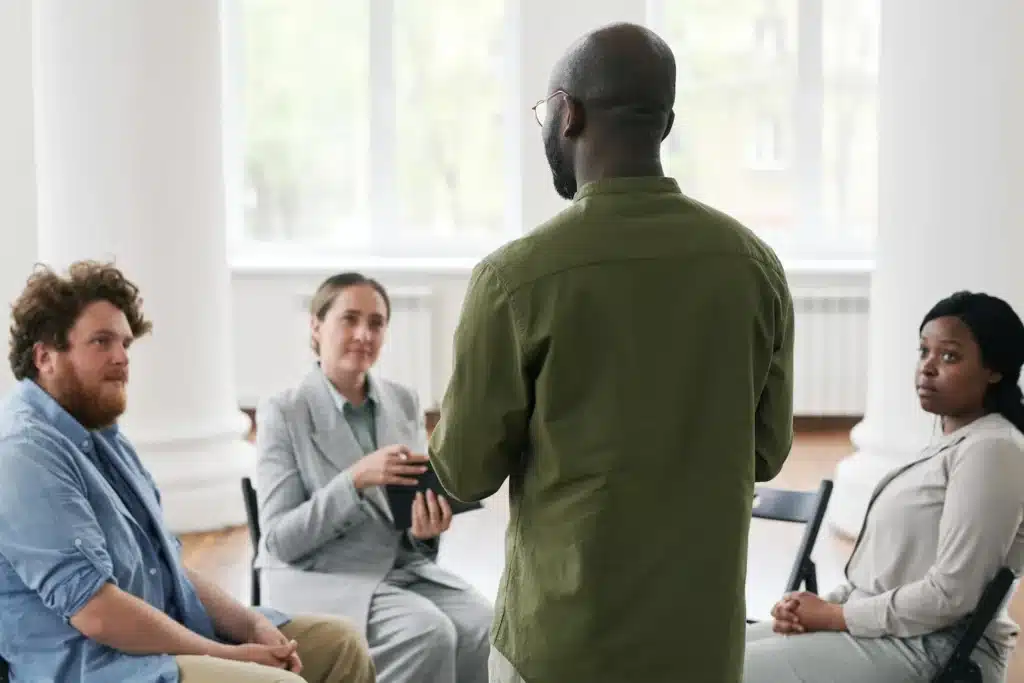 group of adults sitting in a circle talking with therapist