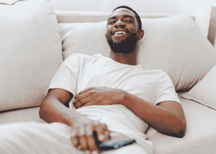 Man laying on couch smiling after support with chronic illness and mental health