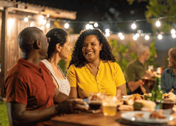 Woman sat outside eating meal with friends after seeking support with gut-brain axis