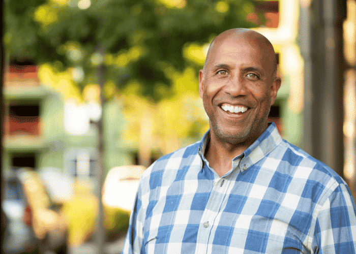 Man standing on street with trees in background smiling after support with HPA axis dysfunction