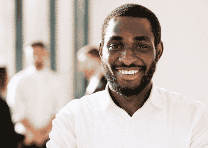 Man standing outside office building with colleagues in the background smiling after support with inflammation and mental health