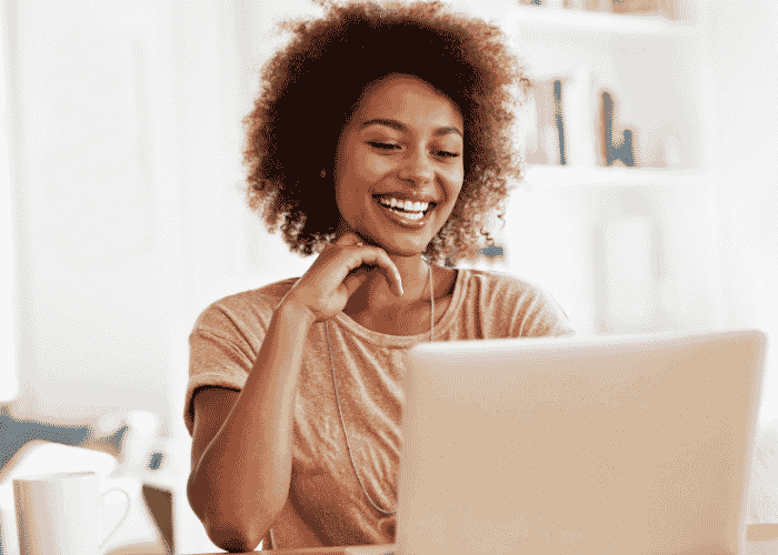 Woman working from home using laptop at desk smiling after support with serotonin and depression