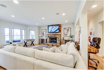 Bright open living room with stone fireplace and plush sectional at a Mission Connection outpatient facility.